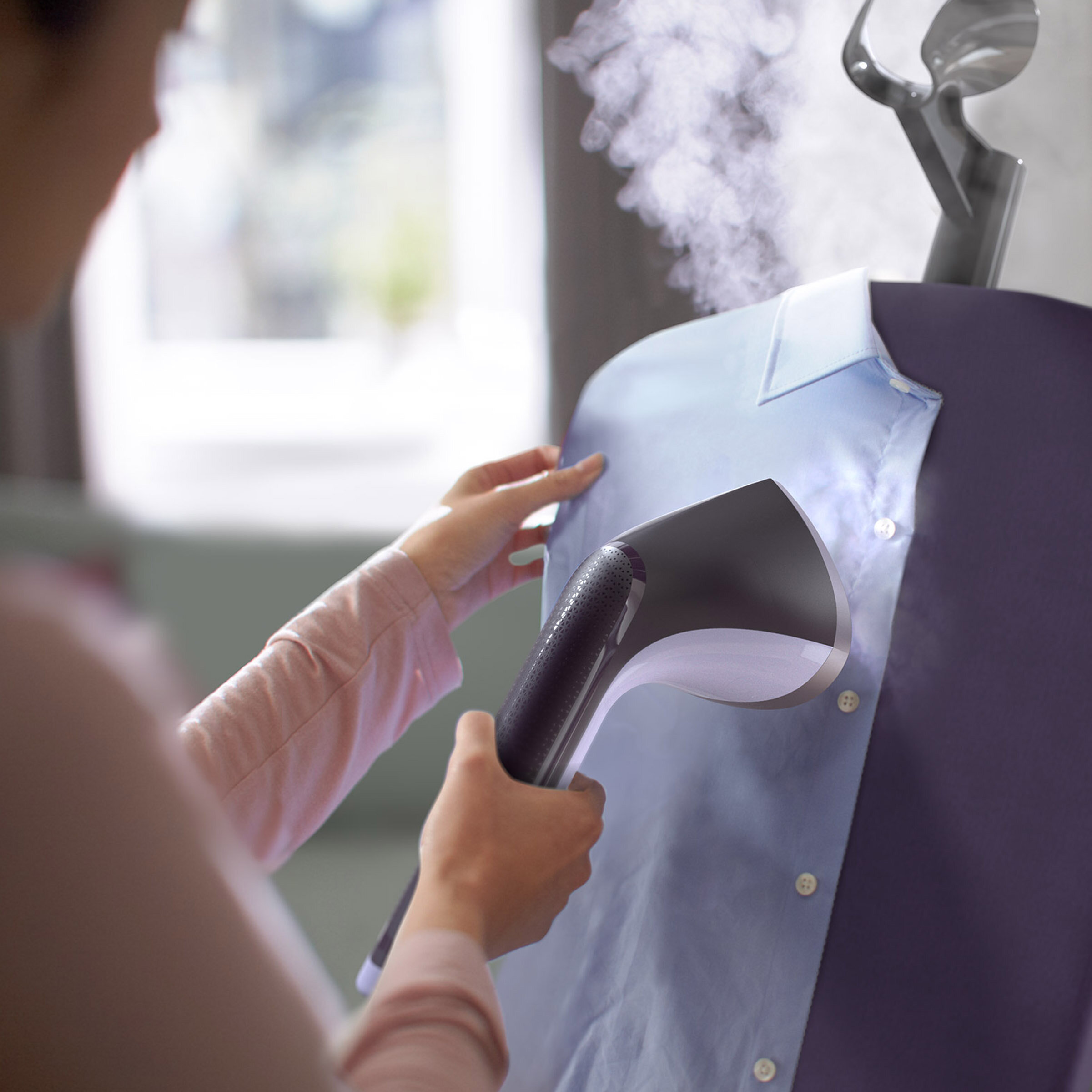 Osoba paruje niebieską koszulę na fioletowym stojaku na ubrania.