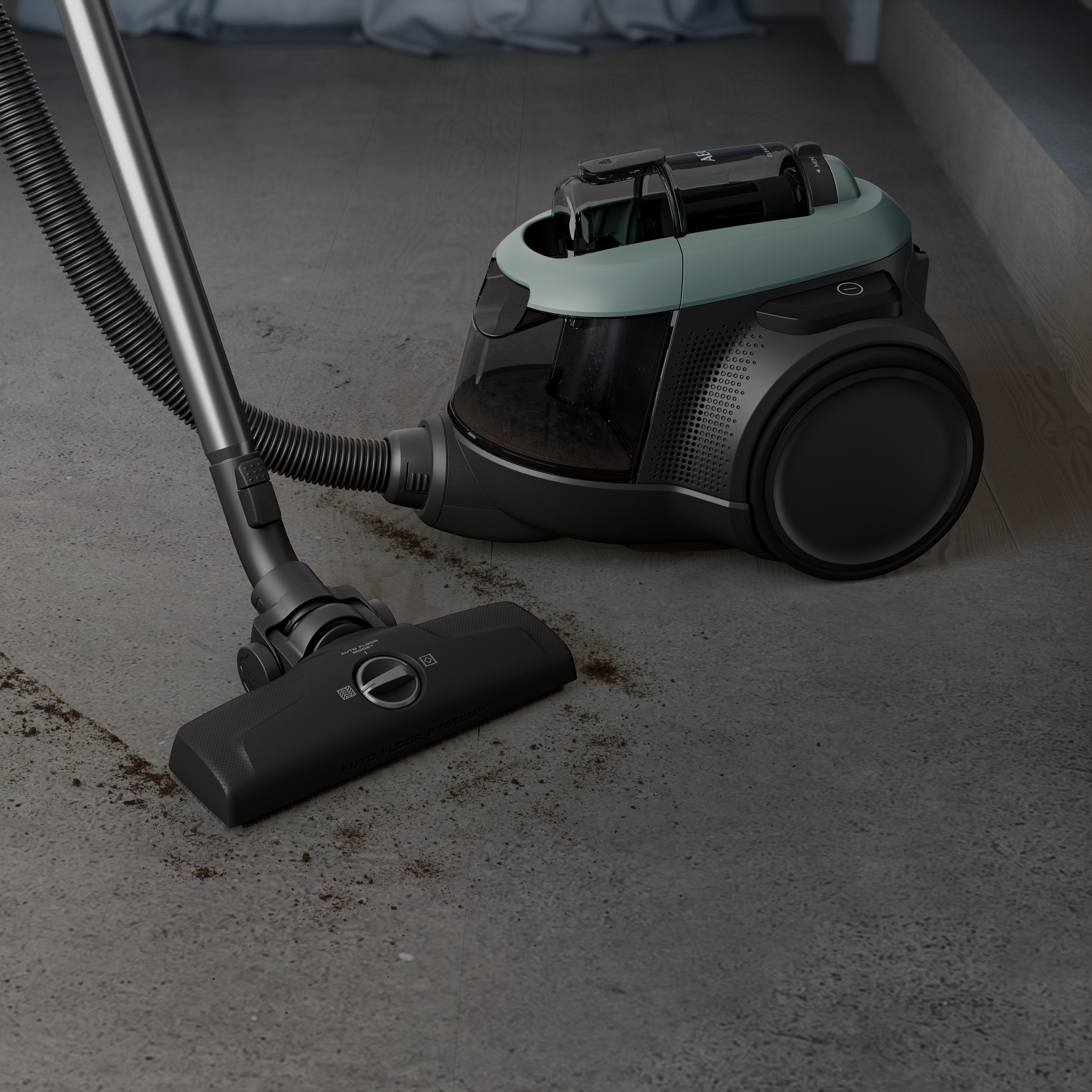 A vacuum cleaner on a gray floor, with dirt around the vacuum head. The vacuum is gray and green.