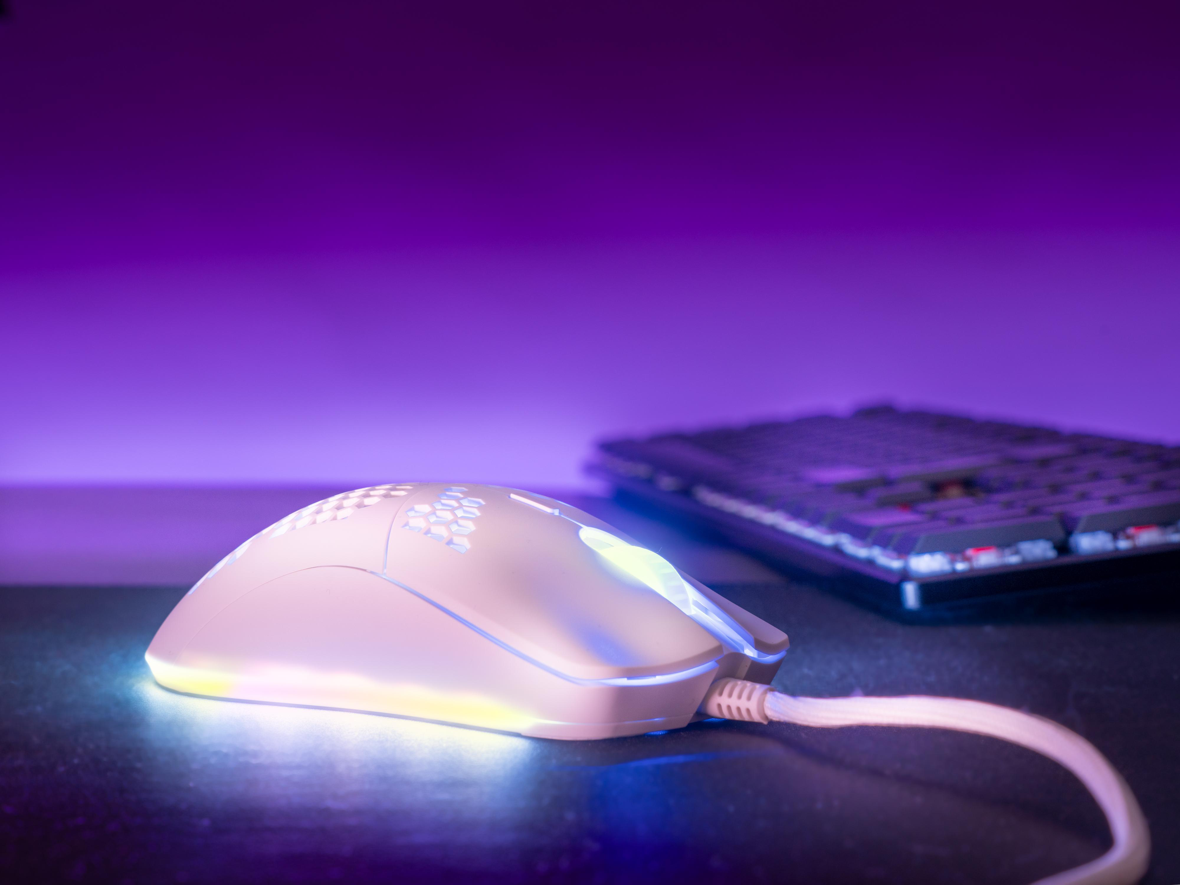 Eine weiße Gaming-Maus mit blauem Licht auf einer lila beleuchteten Oberfläche, Tastatur im Hintergrund.
