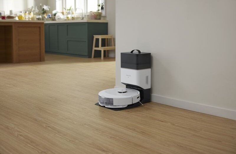 Biały odkurzacz robot i stacja ładująca w pokoju. Nowoczesna konfiguracja czyszczenia.