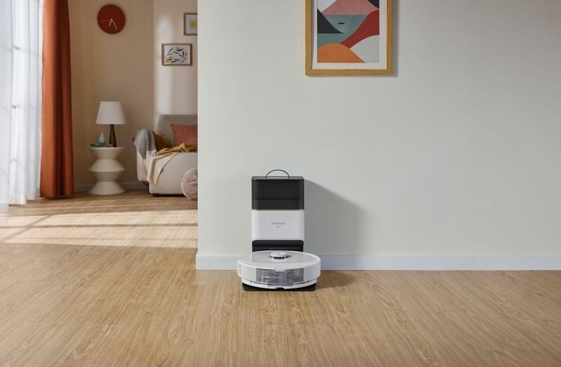 Robot odkurzający i jego stacja ładująca na jasnej drewnianej podłodze.