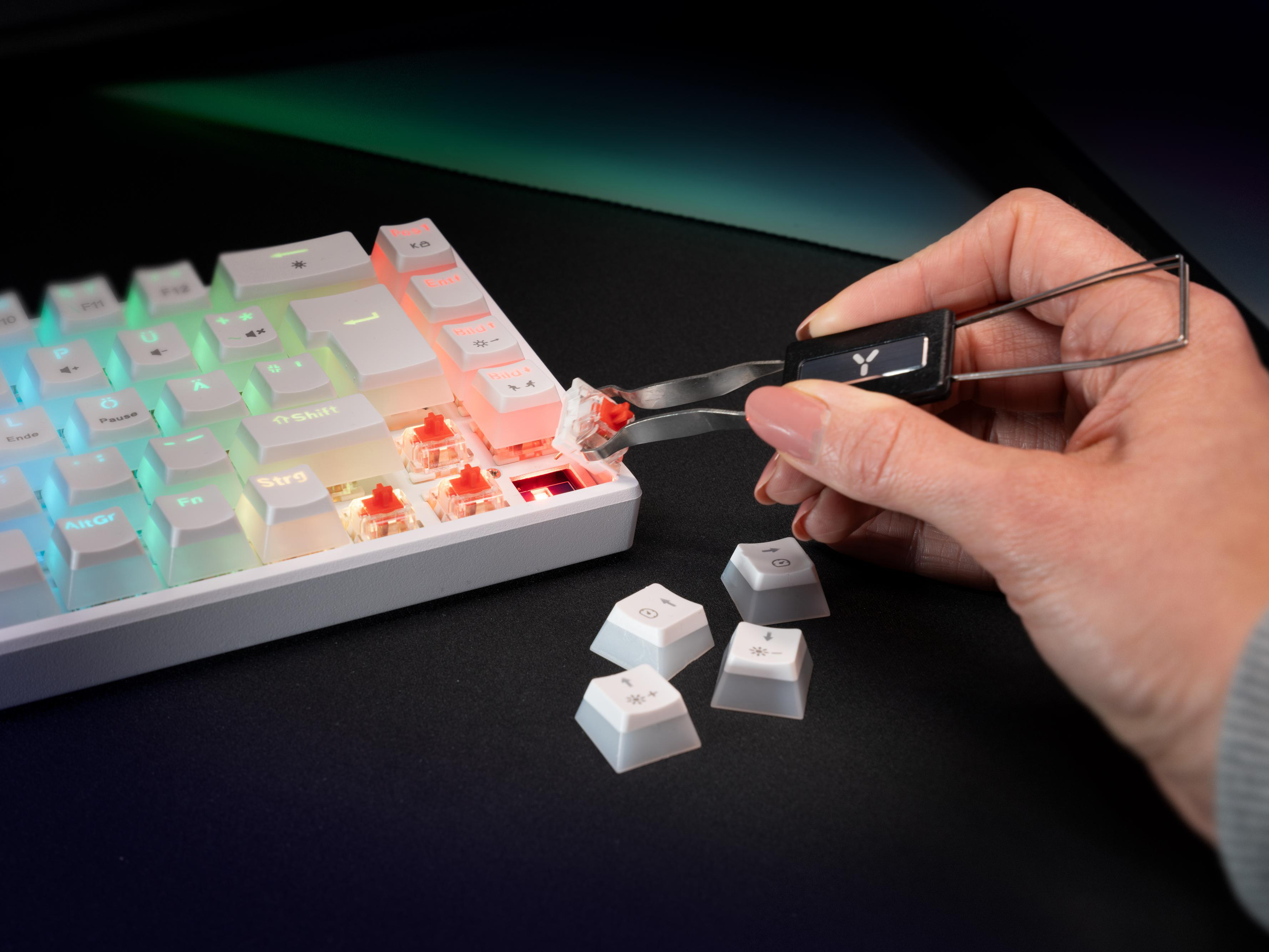 Eine Person benutzt eine Pinzette, um eine Tastenkappe von einer weißen Tastatur zu entfernen.