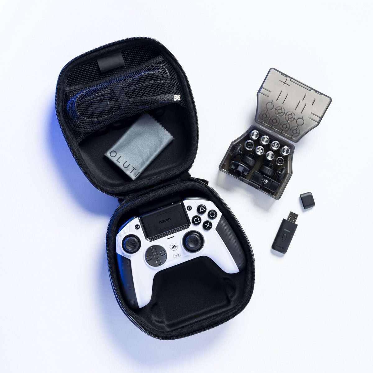 Une manette de jeu blanche est ouverte dans un étui noir, avec des accessoires à côté.
