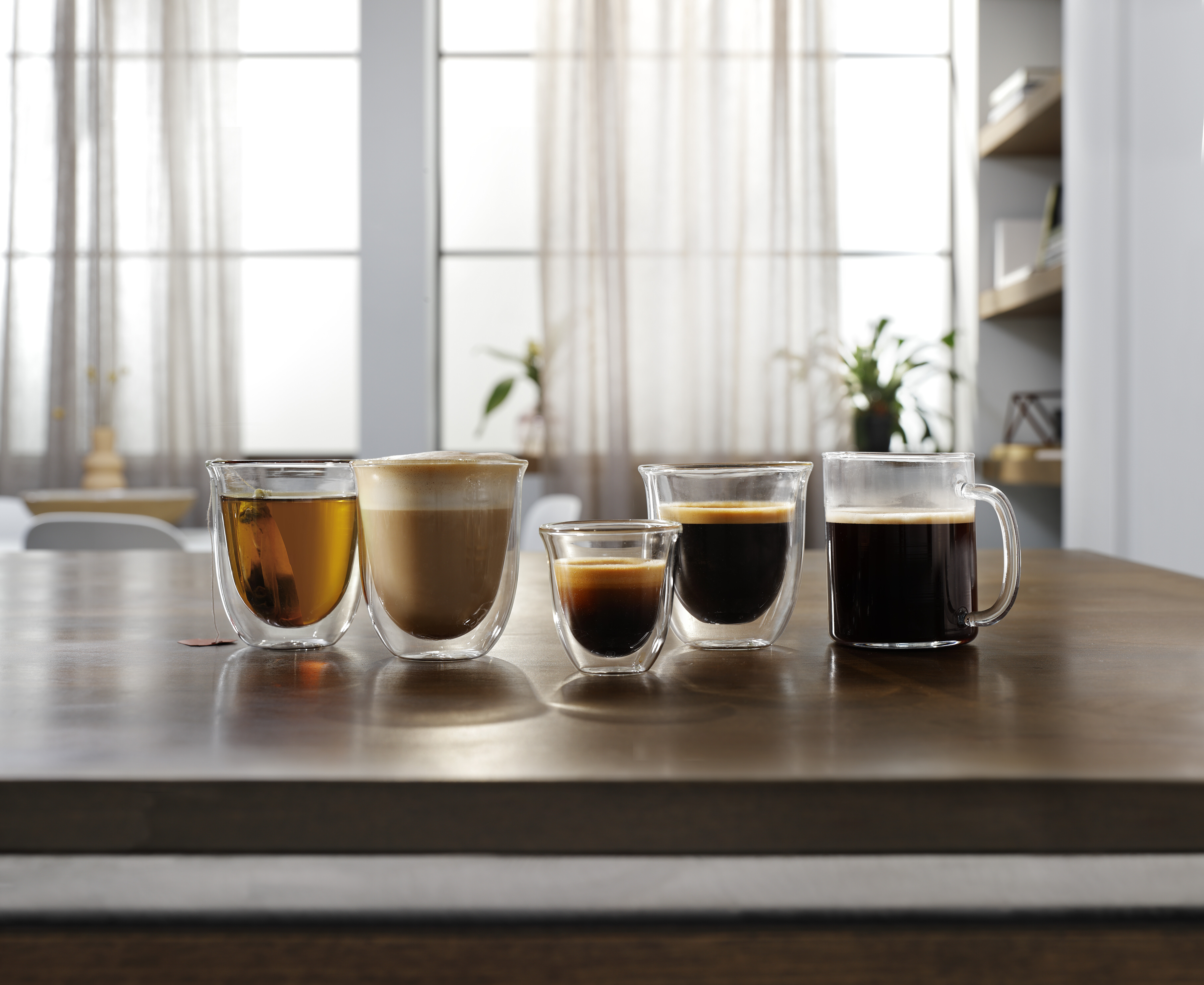 Cinco bebidas de café diferentes en vasos de vidrio sobre mesa madera.