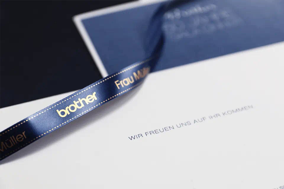 Blaues Band mit goldenem Text auf weißem Papier mit Text. Dunkler Hintergrund.