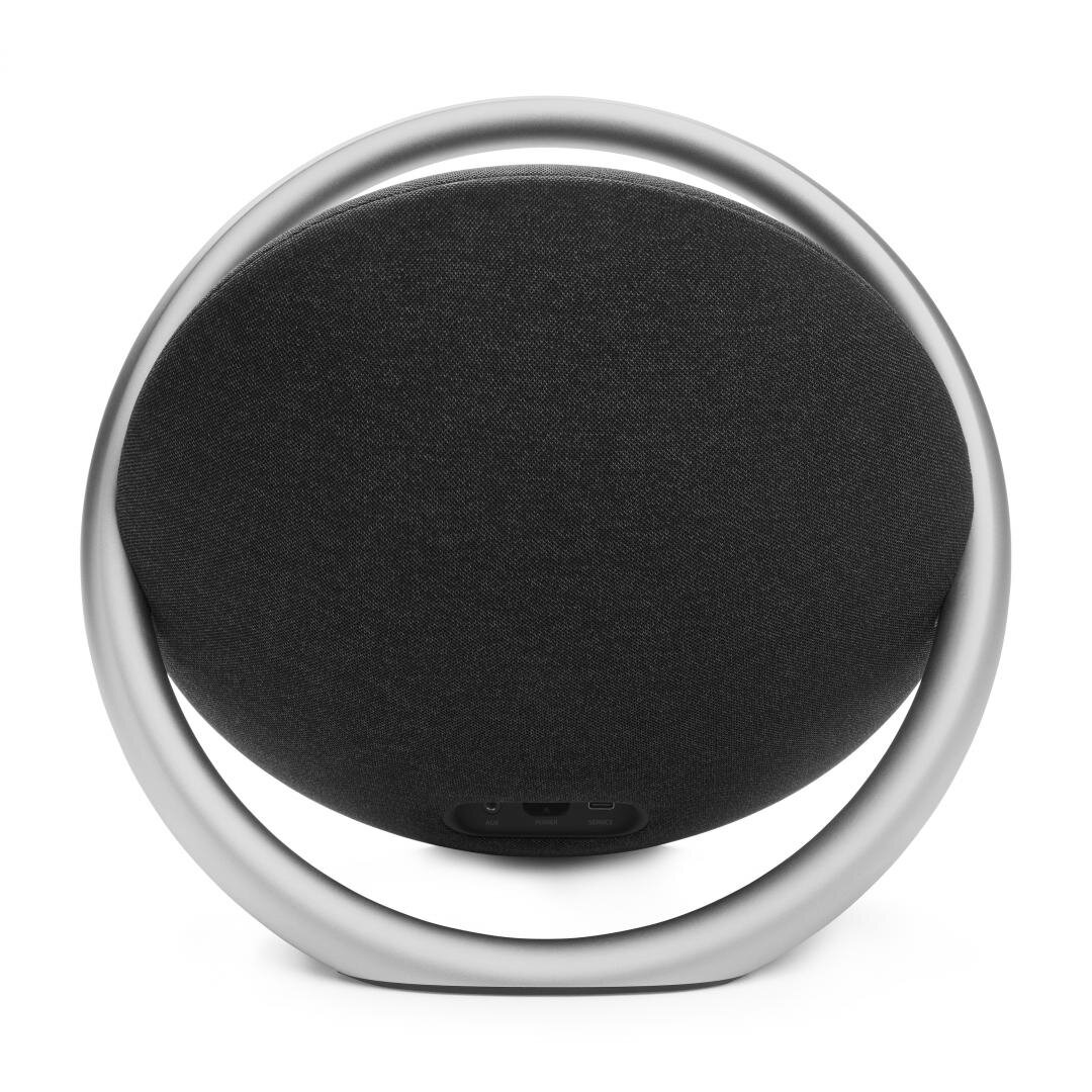 Okrągły srebrny głośnik z czarnym przodem. Białe tło.