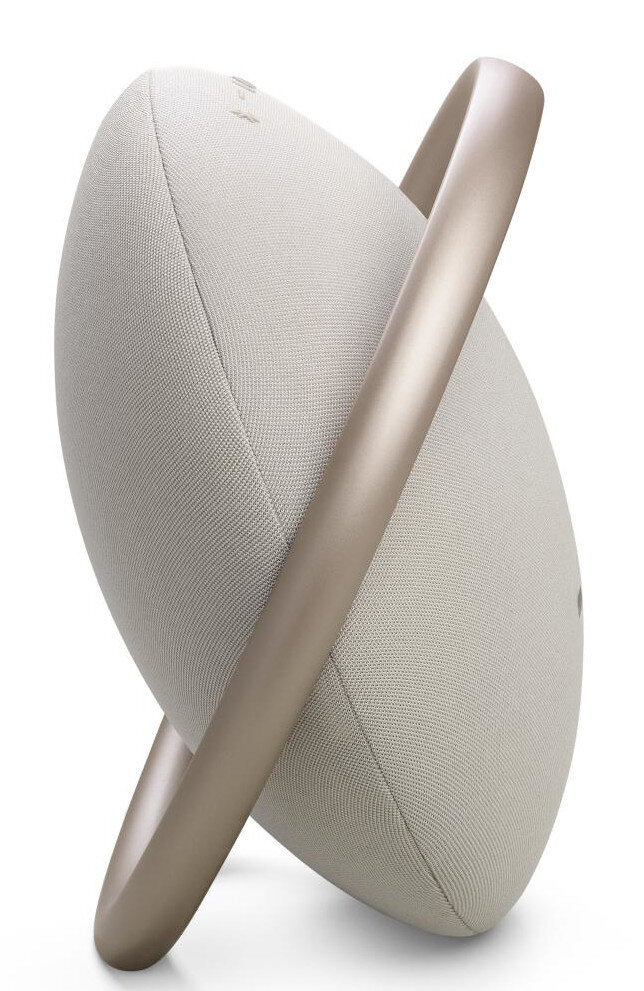 Beżowy głośnik z metalowym uchwytem. Głośnik jest owalny i ustawiony na białym tle.