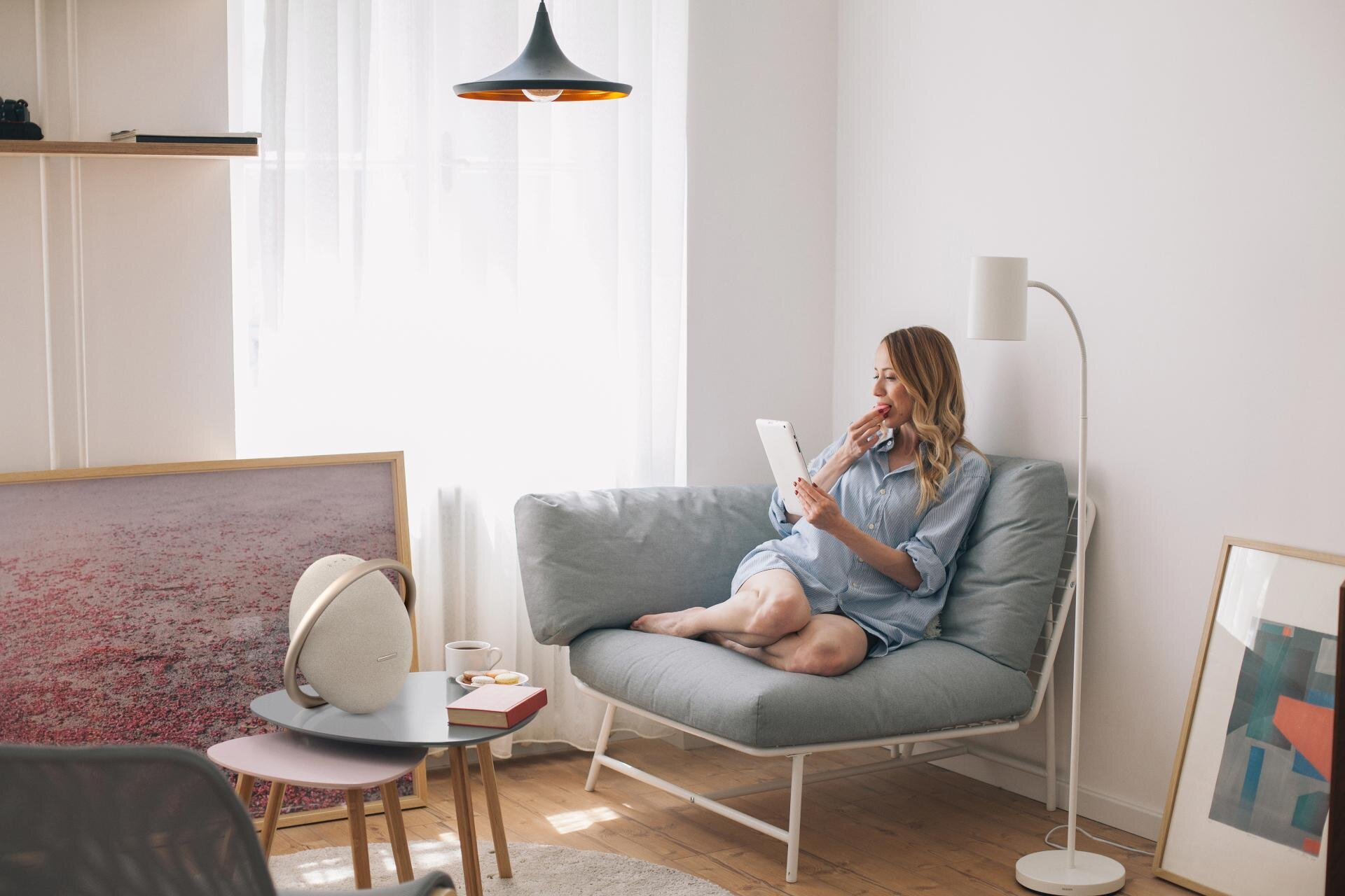 Kobieta z tabletem w salonie. Głośnik na stole. Nowoczesne meble i oświetlenie.