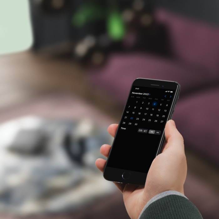 Een hand houdt een telefoon vast met een kalender voor november 2022.