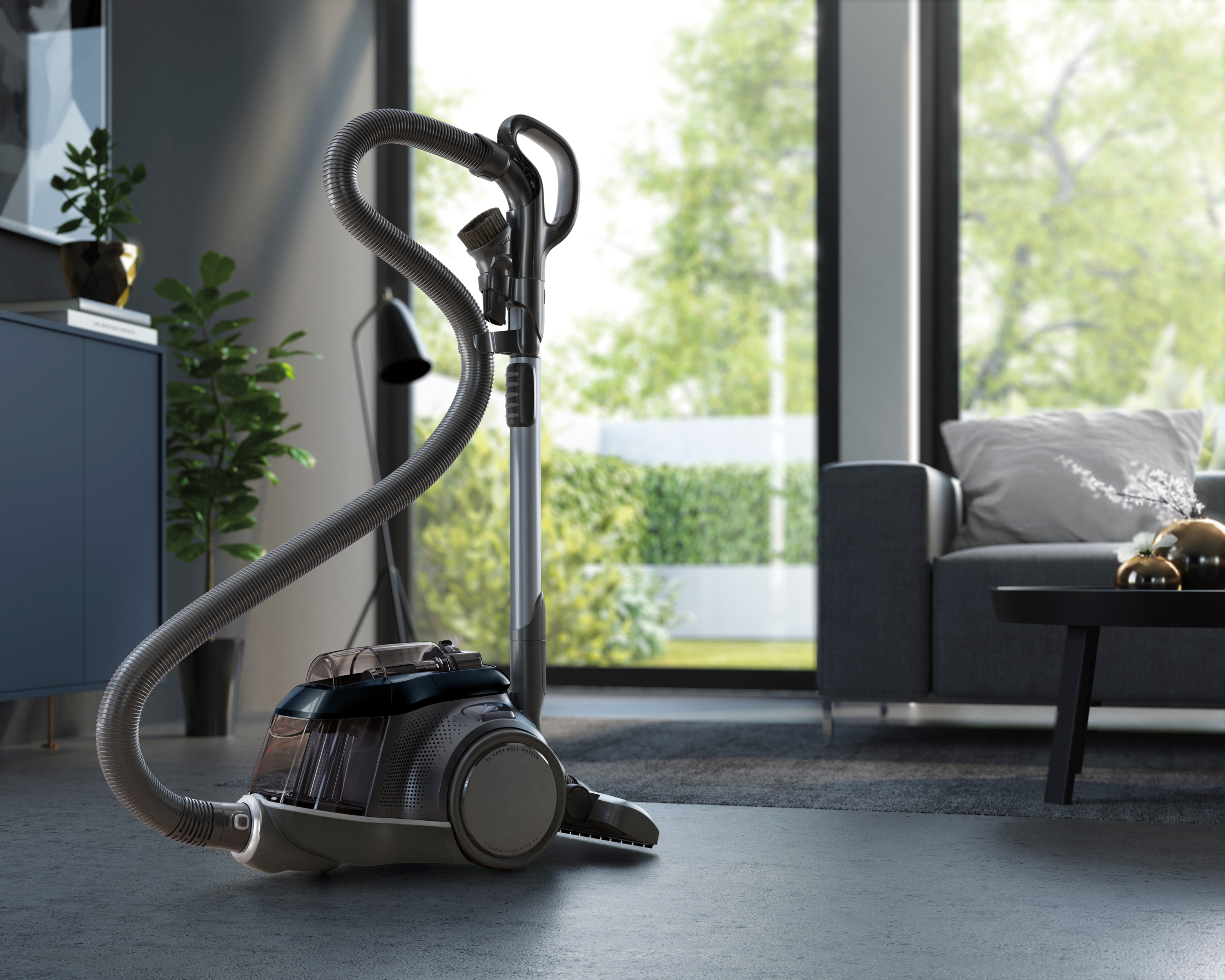 Aspirateur dans une pièce. L'image montre l'aspirateur, le tuyau et un salon avec des meubles.