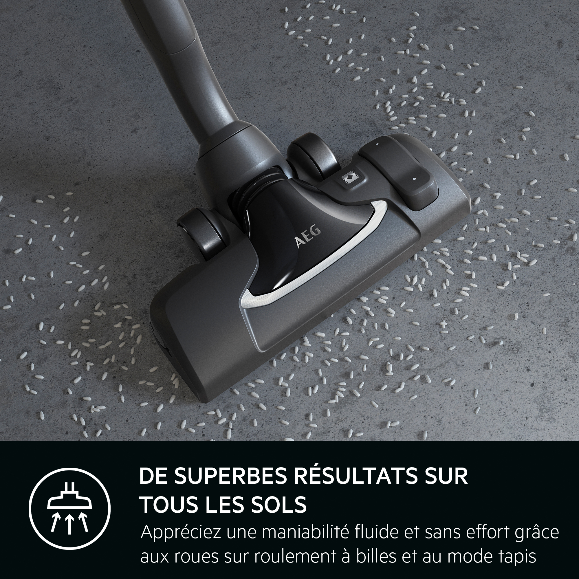 Tête d'aspirateur sur un sol gris avec du riz dessus. Texte en bas.