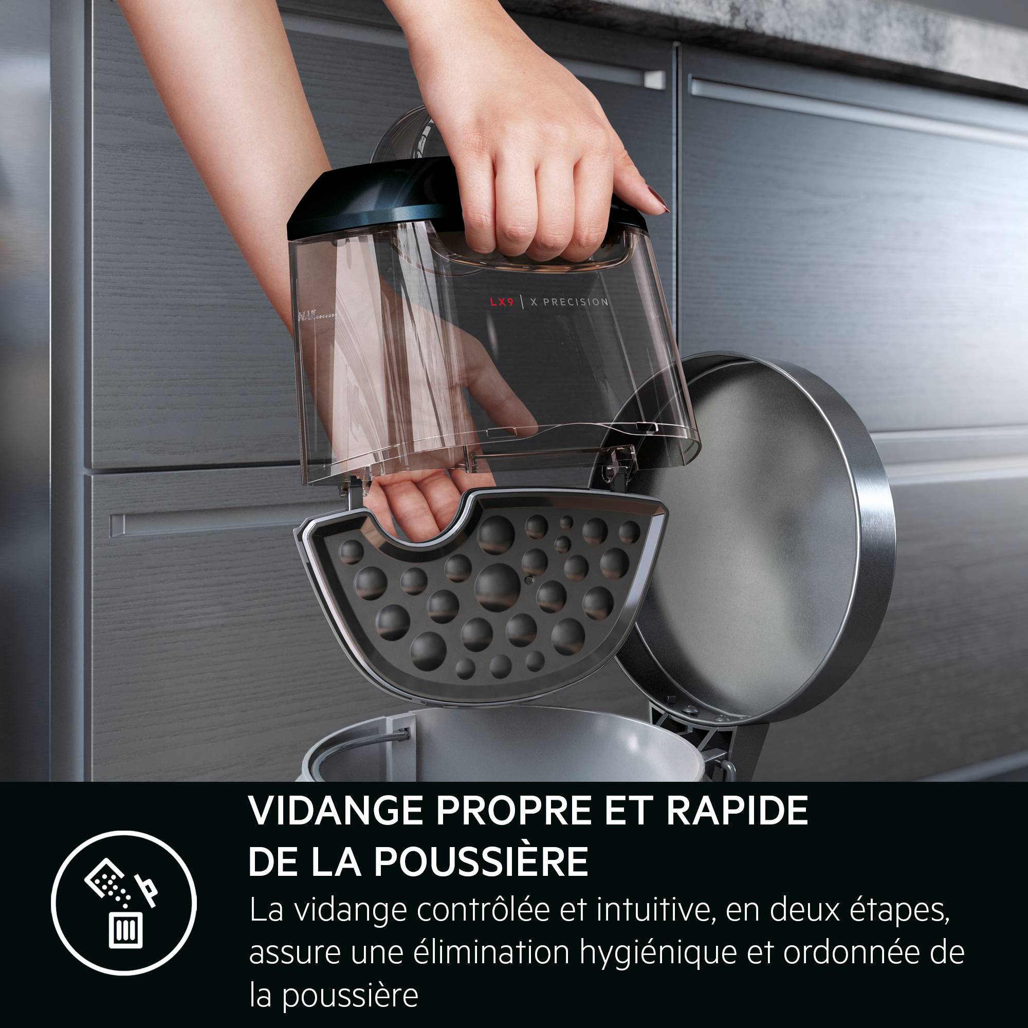 Une main vide un conteneur à poussière d'aspirateur dans une poubelle. Le conteneur est transparent.