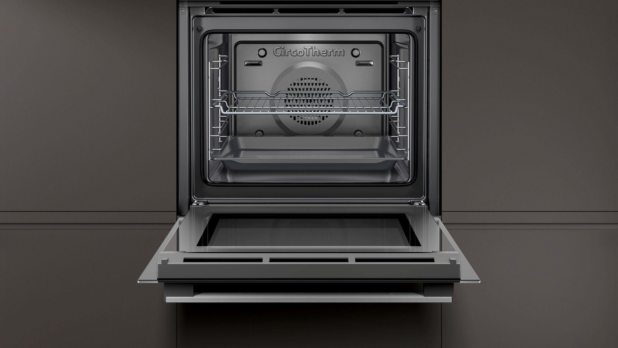 Offener Backofen mit Innenregalen und Tablett. Hintergrund ist eine dunkelgraue Wand.