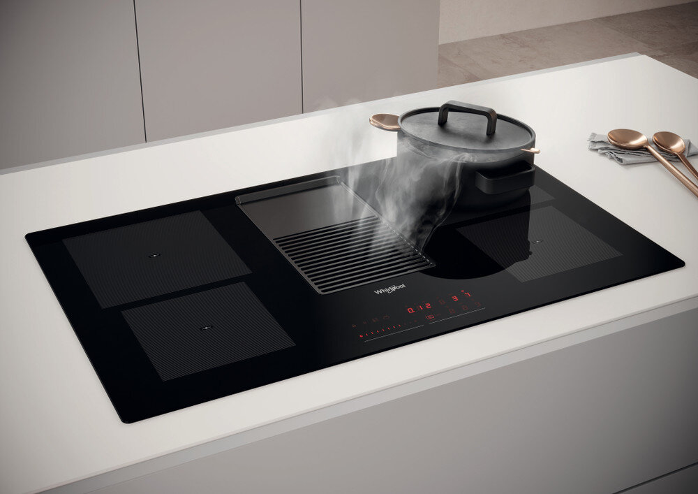 Czarna kuchenka z parą unoszącą się z patelni.