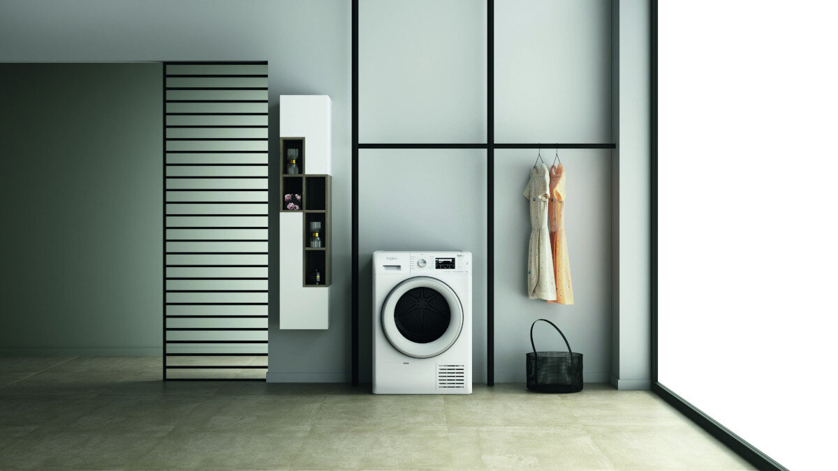 Pralnia z pralką, wiszącymi ubraniami i szafką.