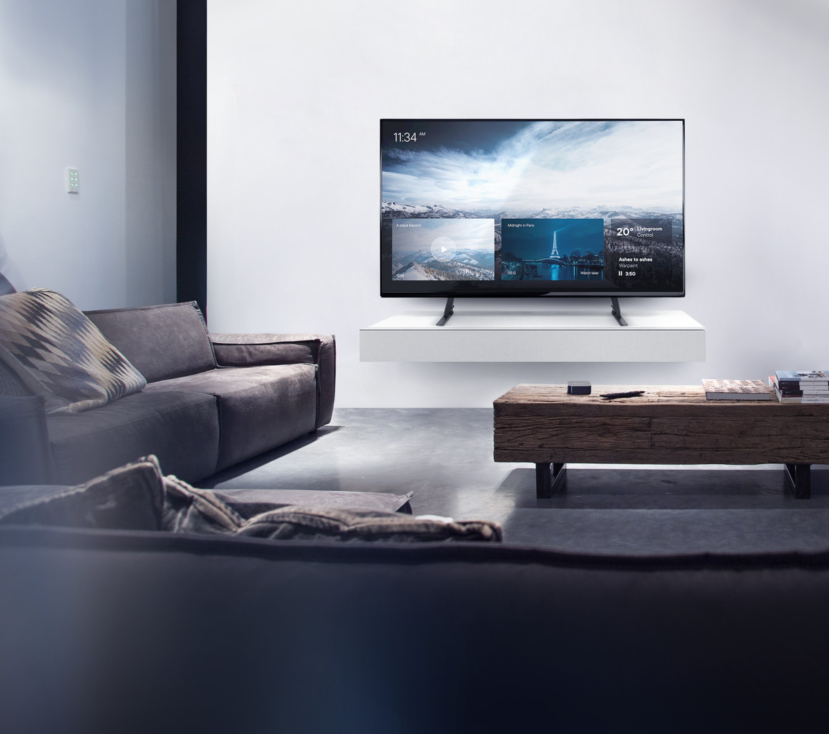 Wohnzimmer mit Fernseher, der eine Stadtszene zeigt. Eine Couch und ein hölzerner Couchtisch befinden sich im Vordergrund.