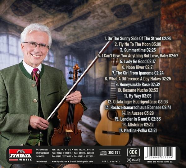 Ein Mann mit Brille und grauem Haar hält eine Violine, trägt Tracht. Musikliste im Hintergrund.
