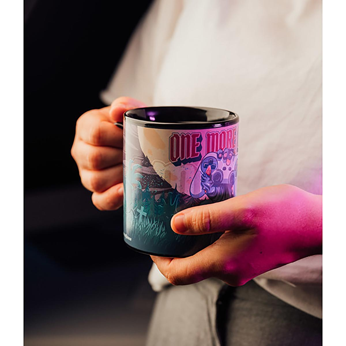 Hände einer Person, die eine Tasse mit farbenfrohem Design halten.