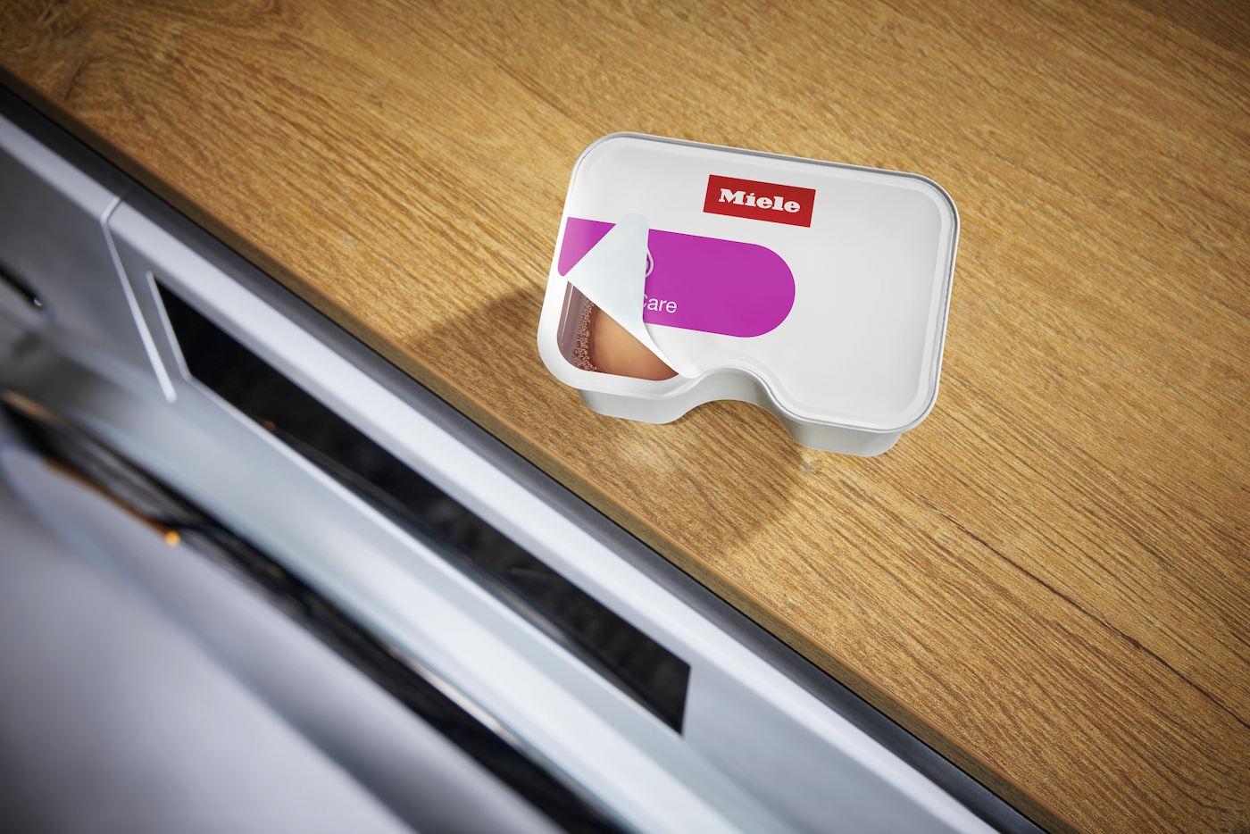 Miele Pflegeprodukt auf Holzboden, teilweise geöffnet.