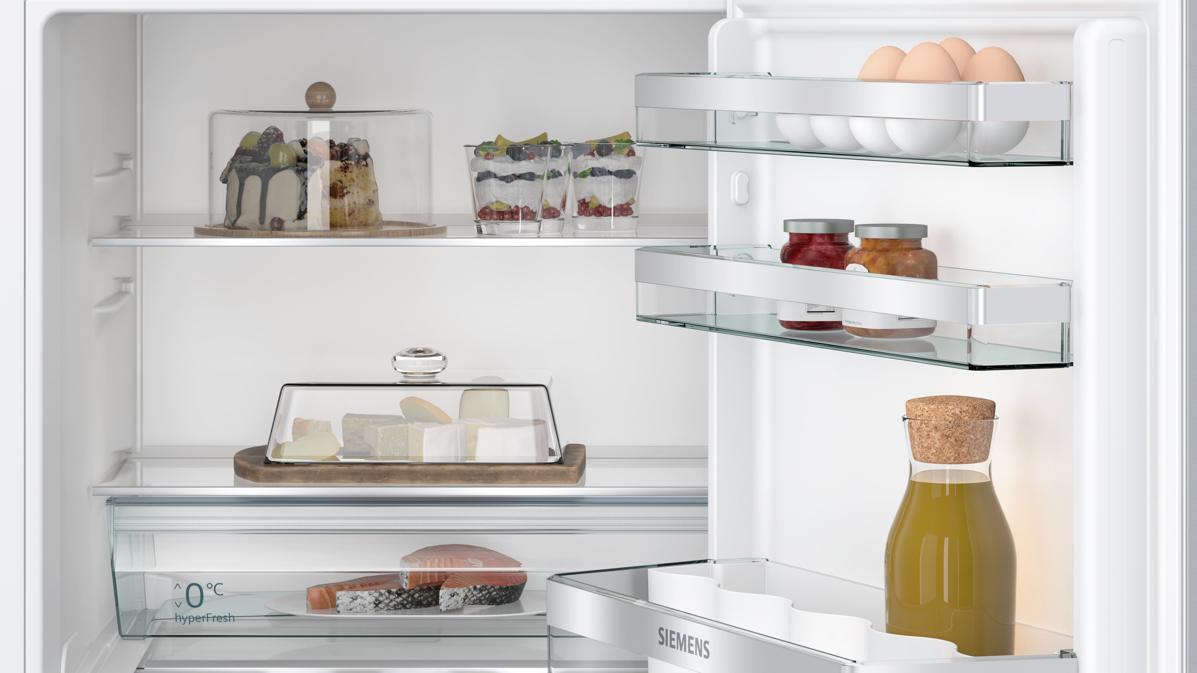 Kühlschrankinnenraum gefüllt mit Lebensmitteln. Enthält Kuchen, Käse, Marmeladen, Eier und eine Flüssigkeitsflasche.