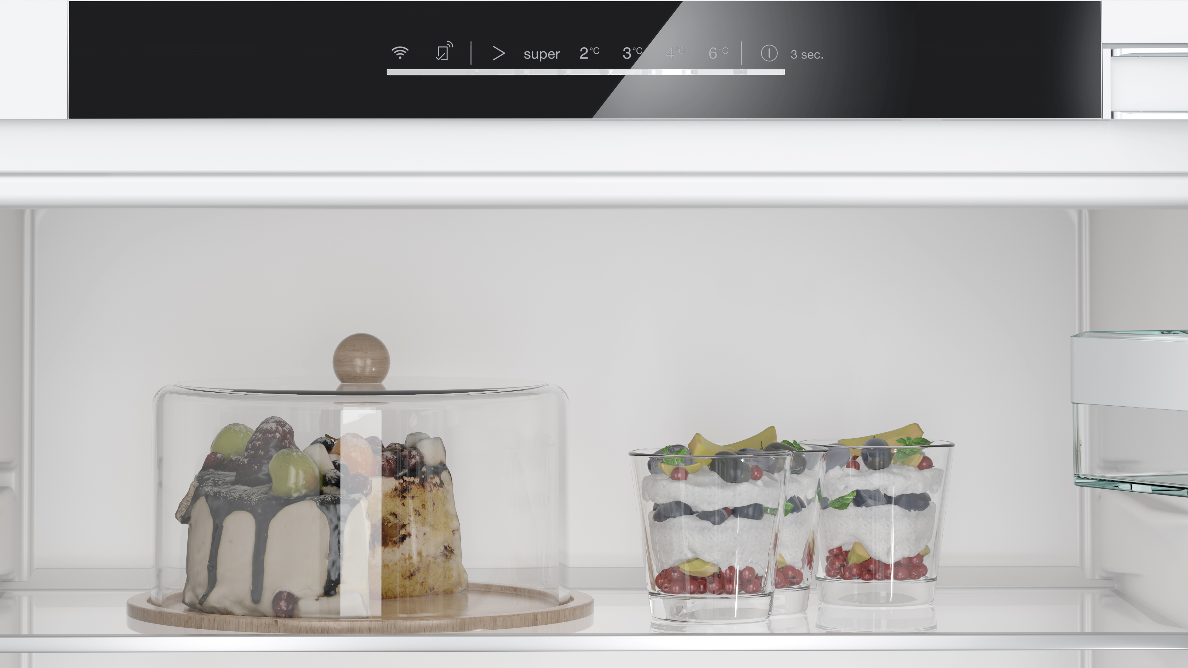 In einem Kühlschrank. Kuchen unter Glasabdeckung und drei Desserts in Gläsern.