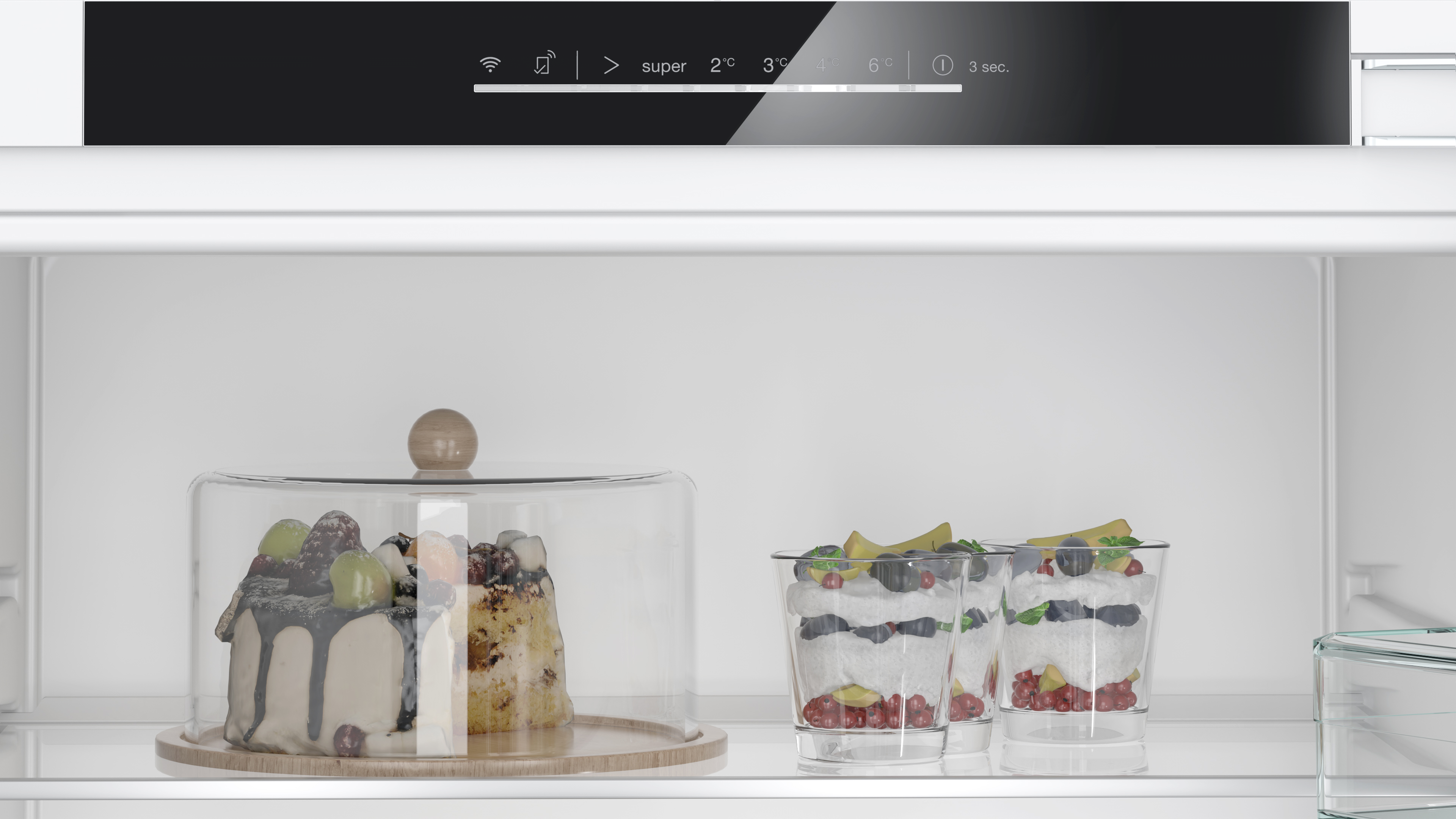 Im Kühlschrank sind ein Kuchen und Desserts in Gläsern auf den Regalen sichtbar.