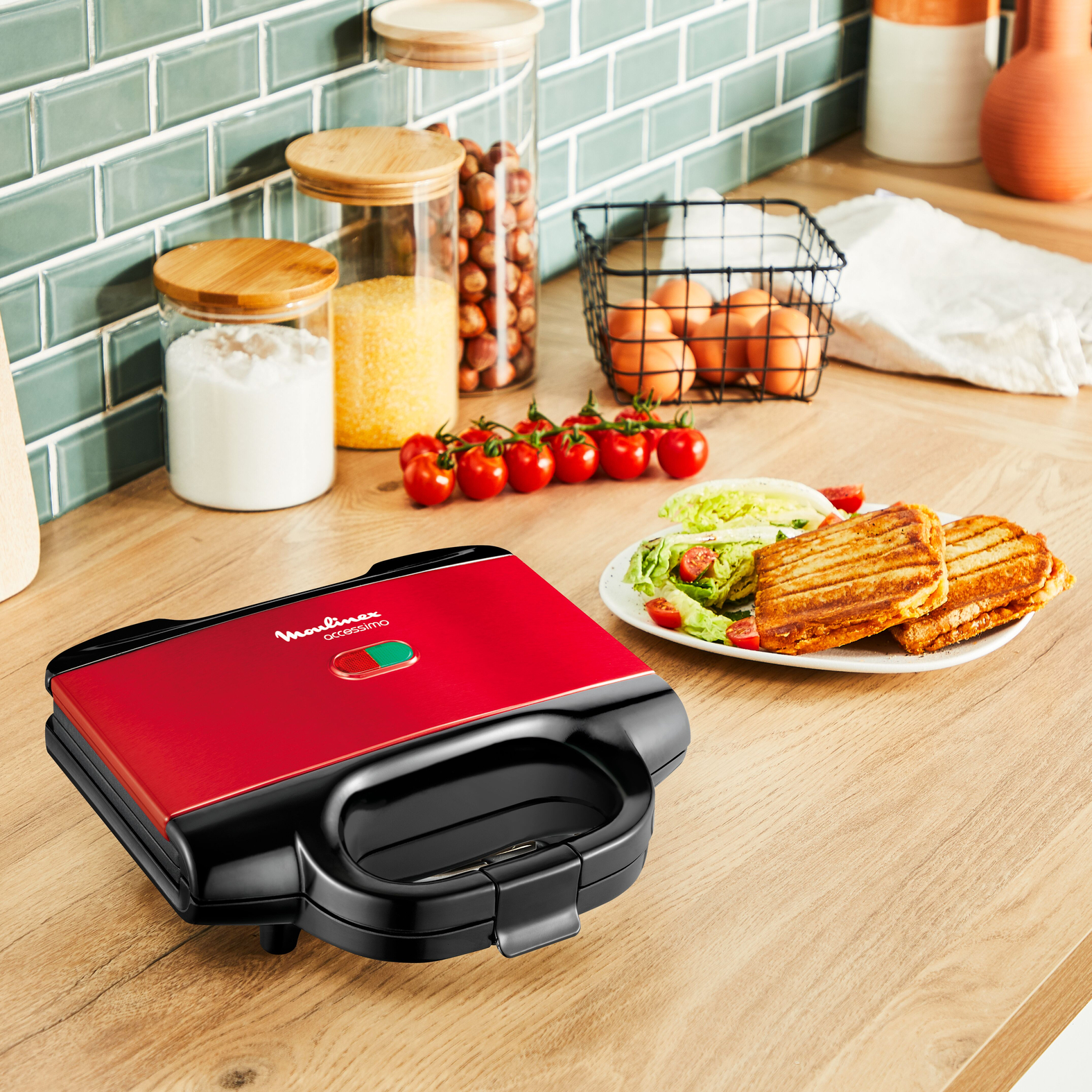 Rode sandwichmaker met eten op een houten aanrecht en ingrediënten.