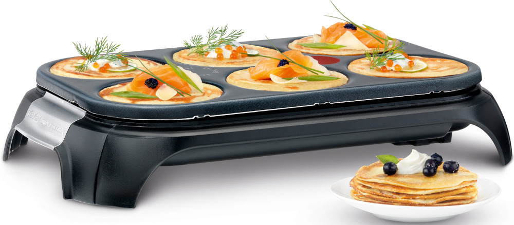 Pannenkoekenpan met gebakken pannenkoeken, sommige belegd met zalm en kaviaar. Een stapel pannenkoeken.