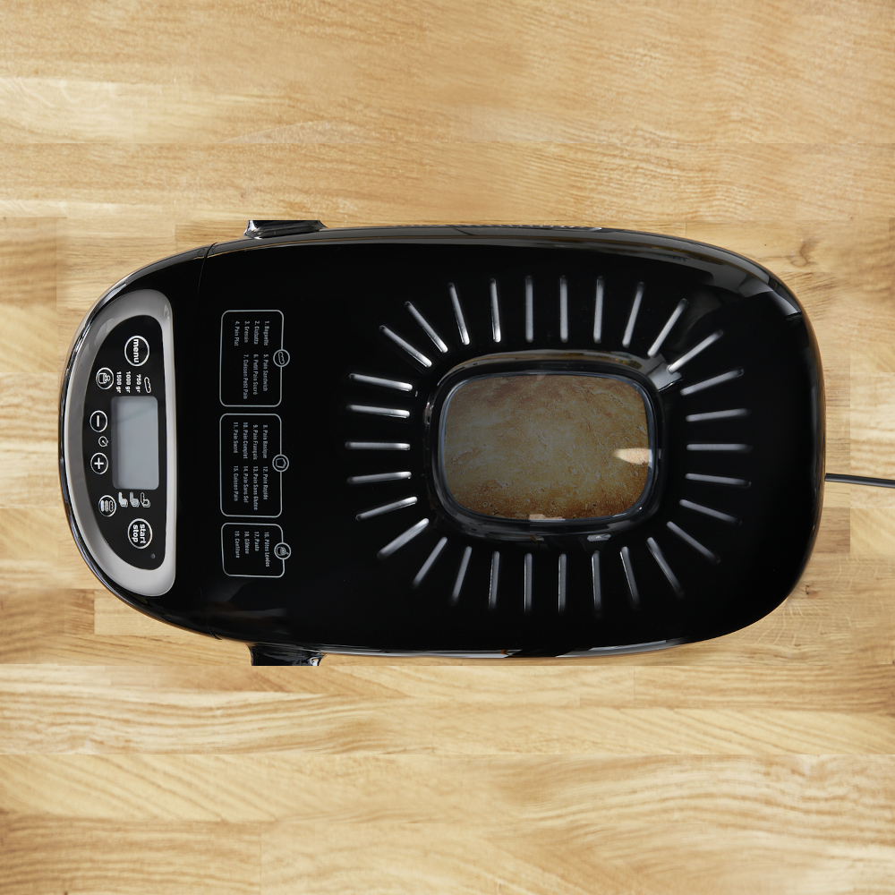 Black bread maker on a wooden table, bread inside.