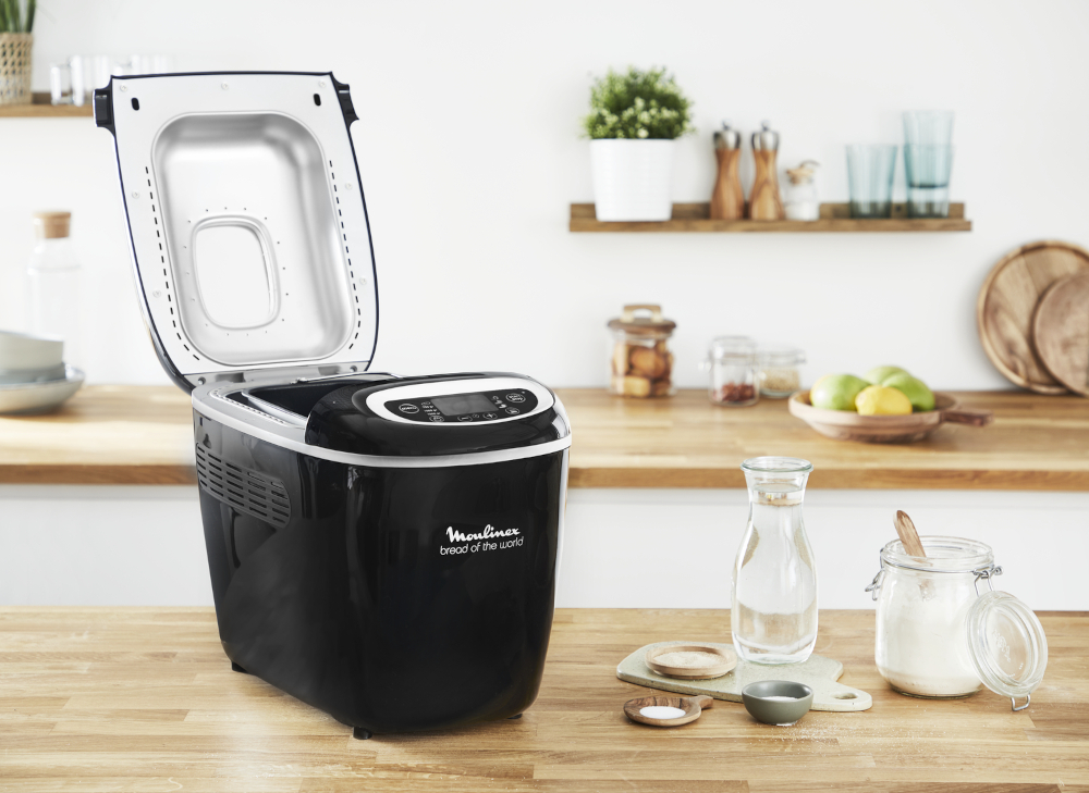 A black and silver bread maker with the lid open.