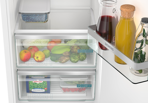 Offener Kühlschrank, Früchte, Gemüse und Saftflaschen. Transparente Schubladen und Regale innen.