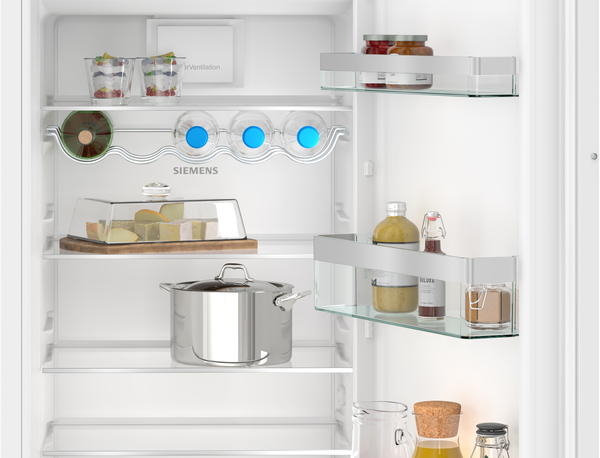 Offener Kühlschrank mit Lebensmitteln auf den Regalen, einschließlich Gläsern und Käse.