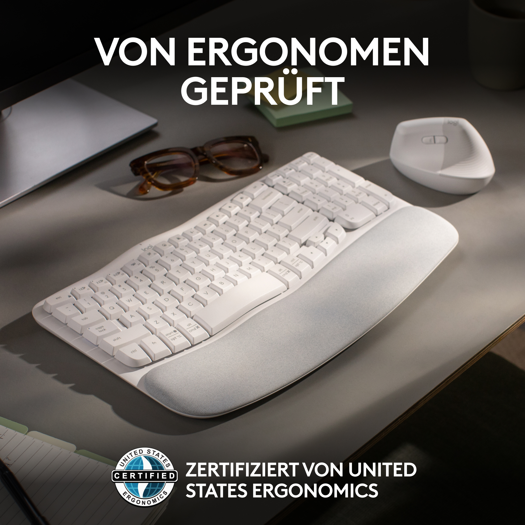 Eine weiße ergonomische Tastatur mit Handballenauflage auf einem grauen Schreibtisch.