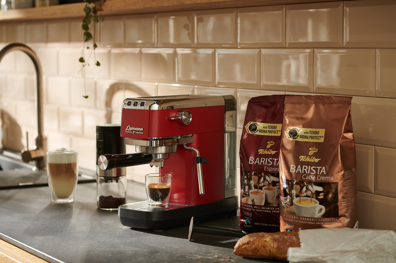 Kahve ve kahve çekirdekleriyle kırmızı espresso makinesi.