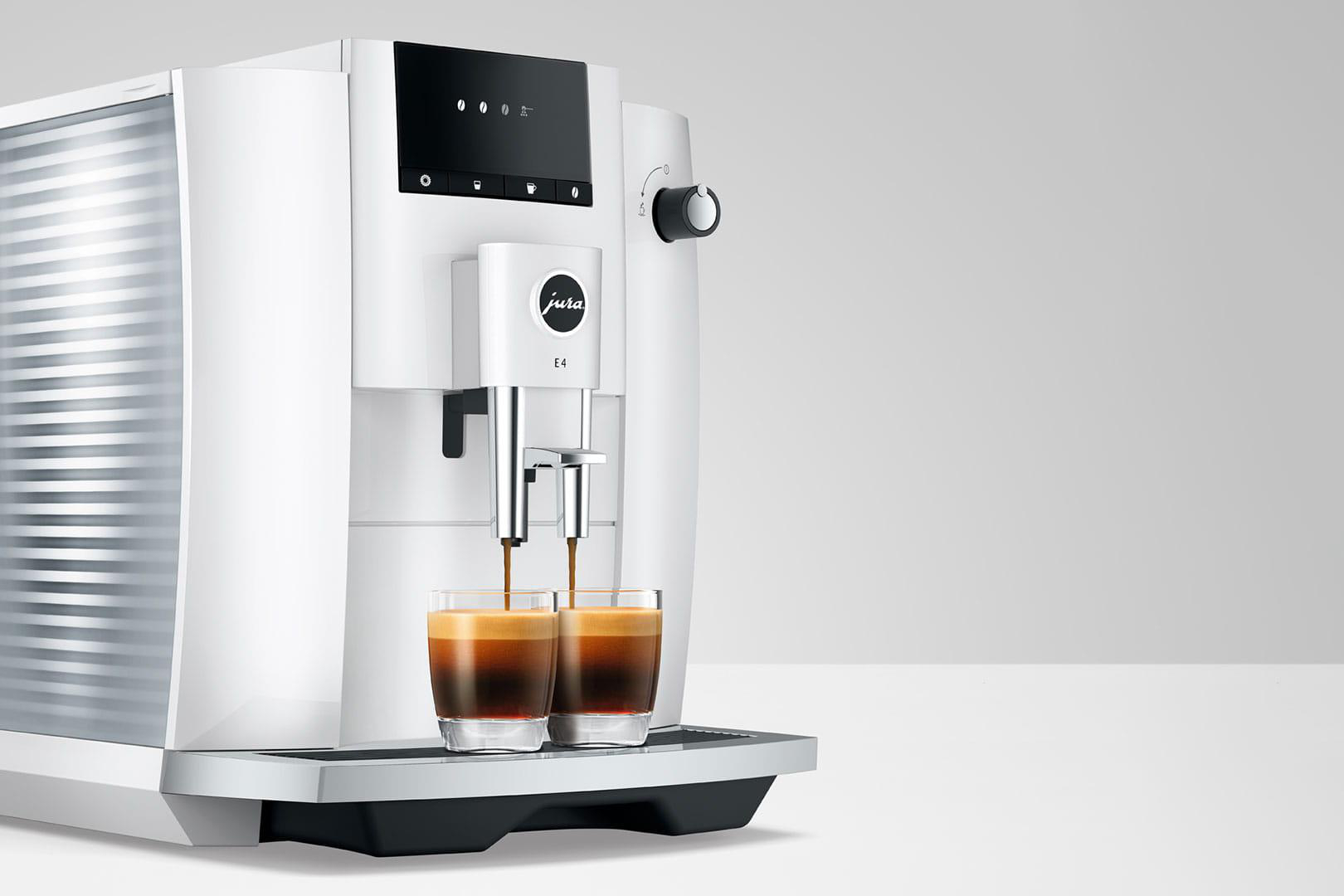 Weiße Jura E4 Kaffeemaschine mit zwei Gläsern, die mit Kaffee gefüllt werden.