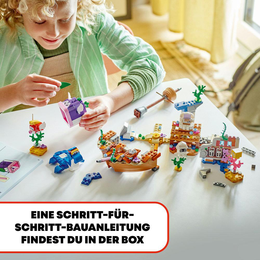 Ein Kind baut ein LEGO-Set. Der Tisch ist weiß mit mehreren LEGO-Teilen und einer Anleitung.
