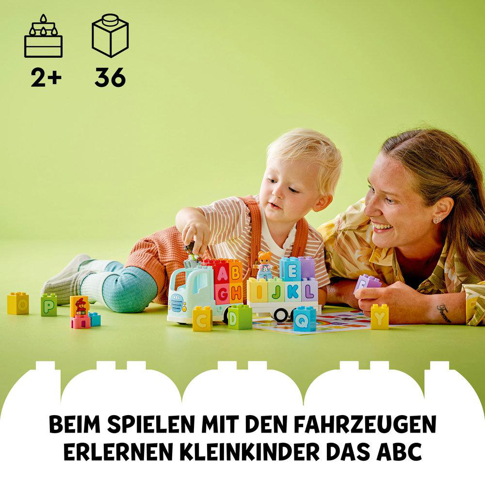 Frau und Kind spielen mit Duplo-Steinen: Spielzeug-LKW und bunte Steine auf grüner Fläche.