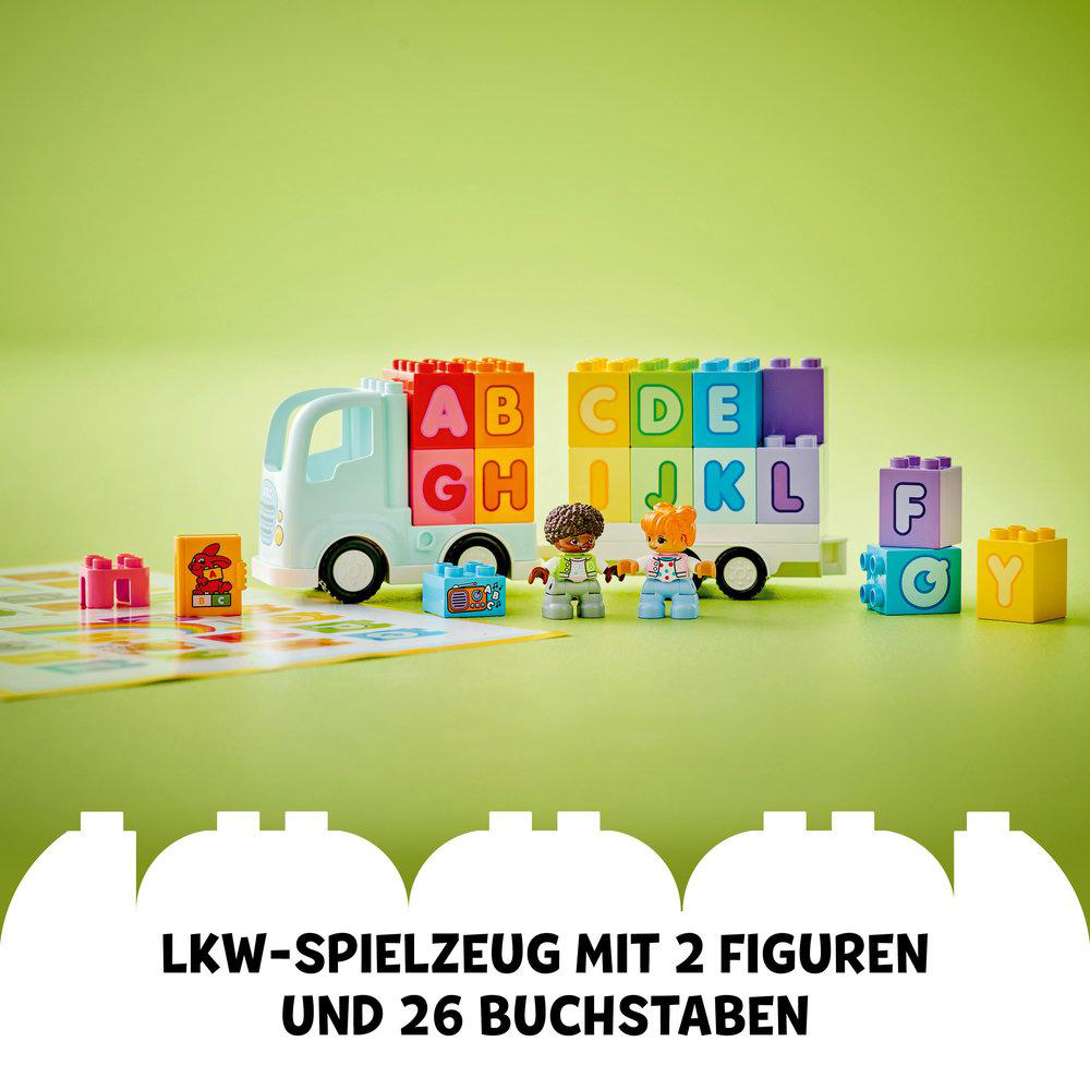 Spielzeug-LKW aus bunten Buchstabenblöcken und zwei Duplo-Figuren. Grüner Hintergrund.