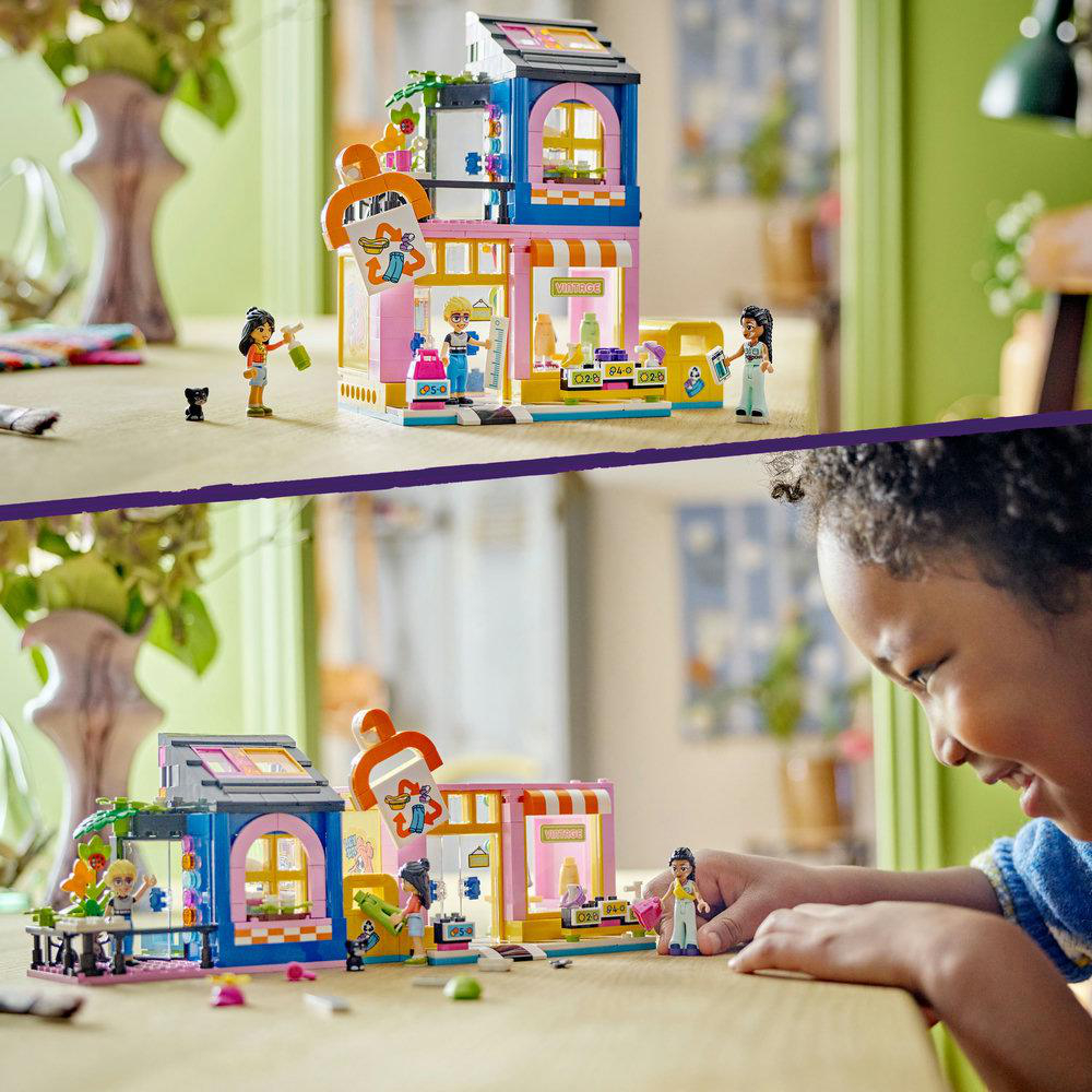 Zwei LEGO-Gebäude von Geschäften, eines rosa und eines blau, mit Kindern, die damit spielen.