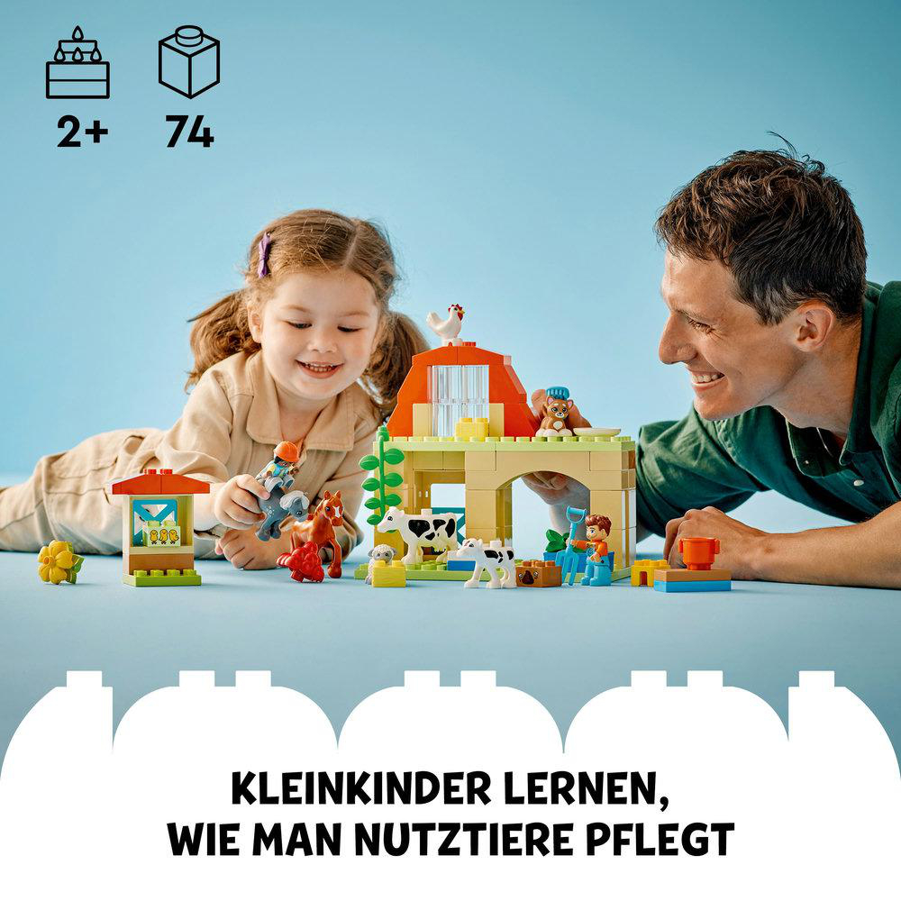 Ein Mädchen und ein Mann spielen mit einem Bauernhofspielzeug, einschließlich Scheune, Tiere und Figuren, auf blauer Oberfläche.