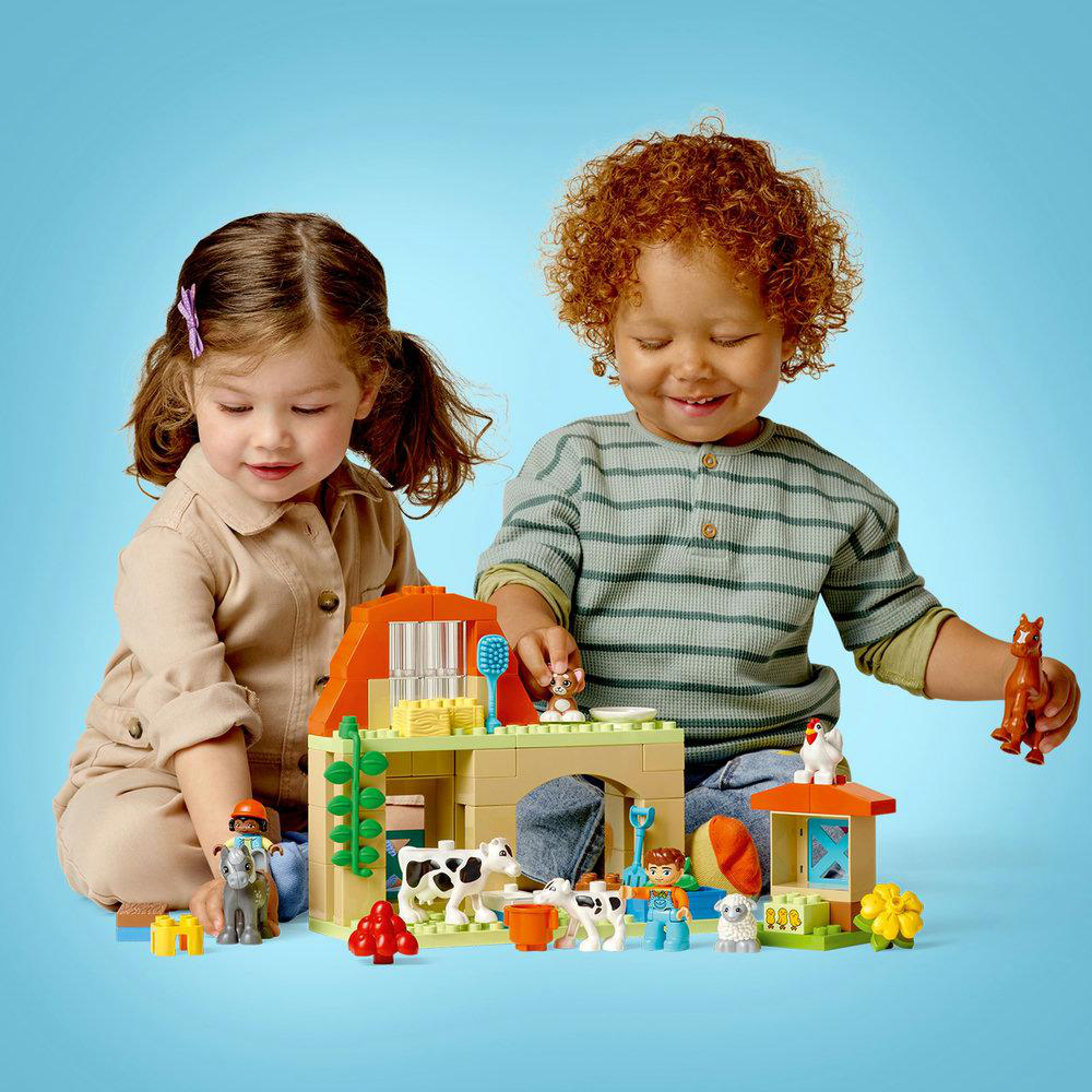 Zwei Kinder spielen mit LEGO-Bauernhof-Set. Enthält Scheune, Tiere und Figuren.