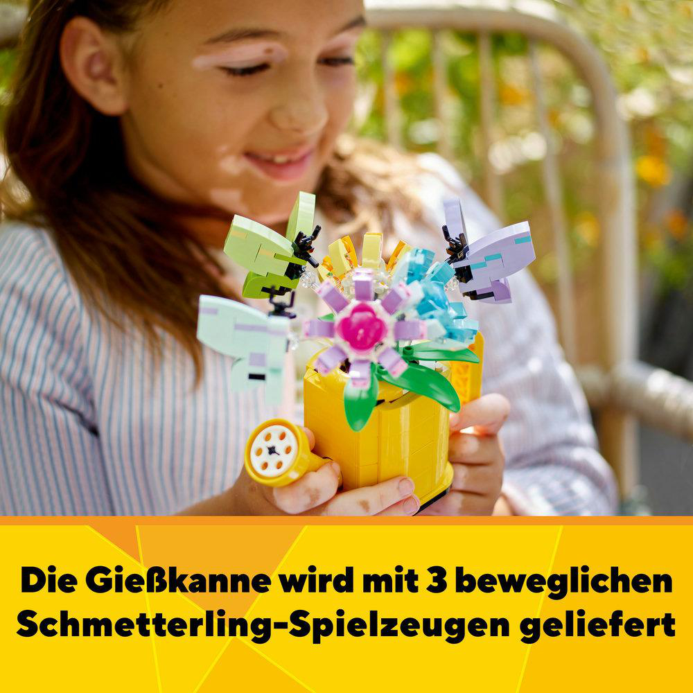 Ein Mädchen hält einen gelben LEGO-Blumentopf mit bunten LEGO-Schmetterlingen.