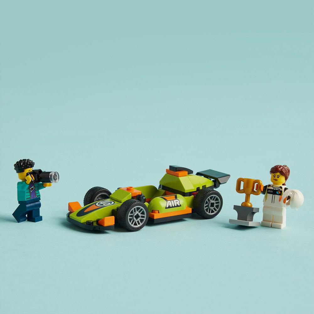 Ein Lego-Rennwagen, Minifiguren eines Rennfahrers mit Trophäe und eines Fotografen auf blauem Grund.