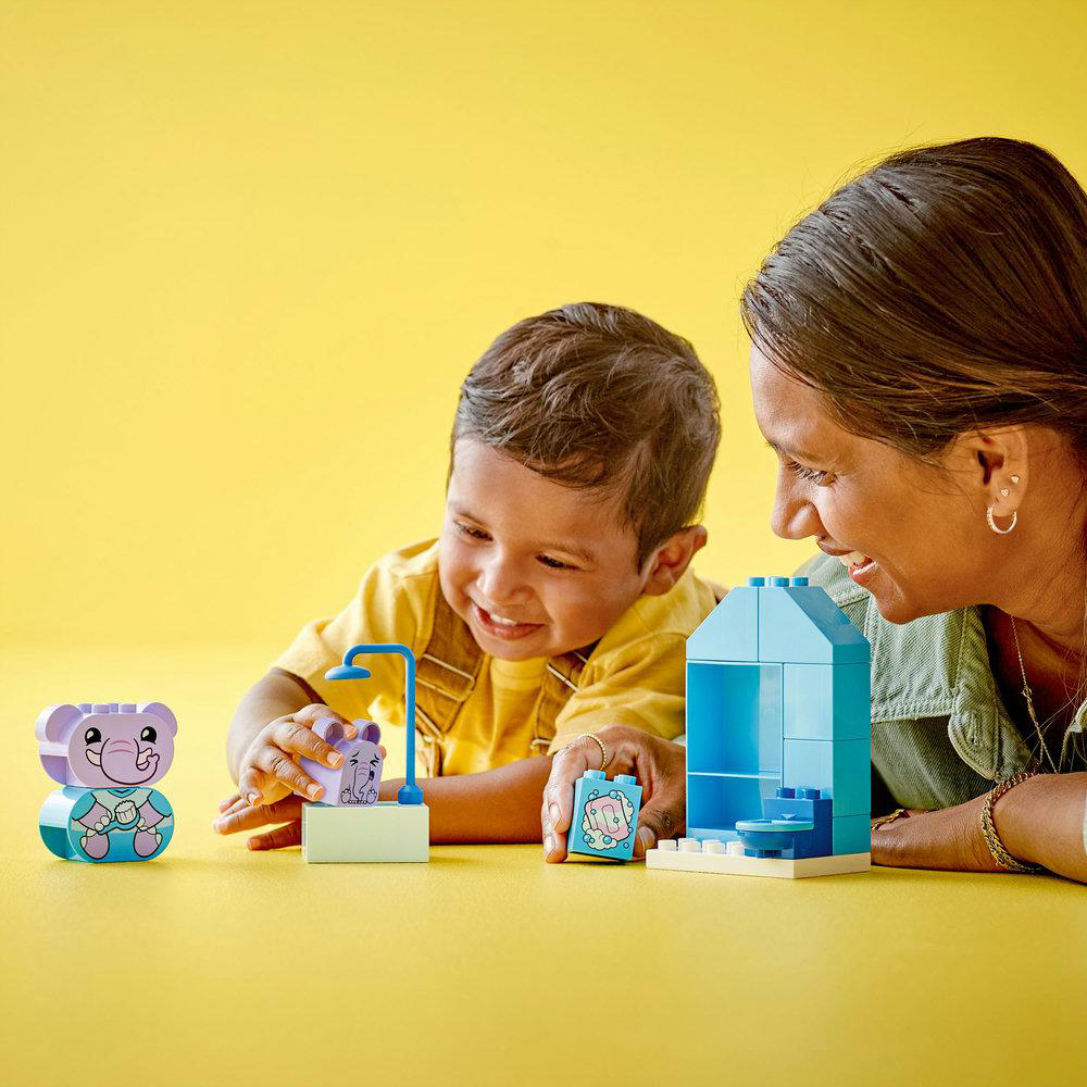 Ein kleiner Junge und eine Frau spielen mit Lego Duplo-Steinen. Sie lächeln und bauen mit den Steinen.