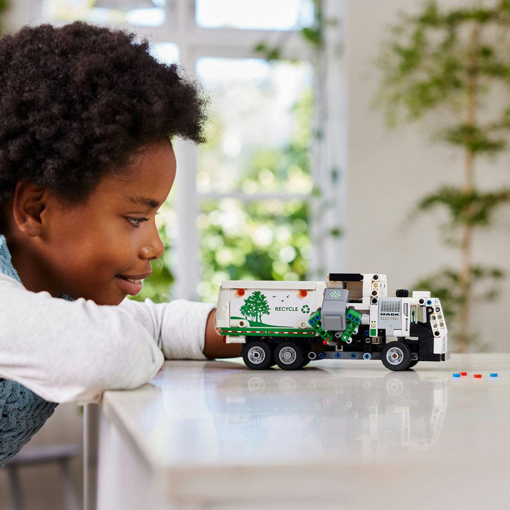 Ein Kind betrachtet einen LEGO Müllwagen auf einem Tisch.