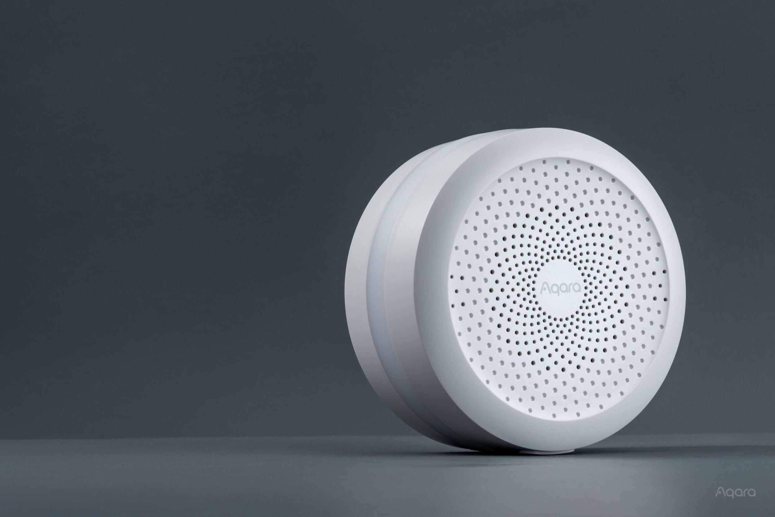 Weißes Aqara Smart Home-Gerät, rund mit zentralem Design aus kleinen Löchern.