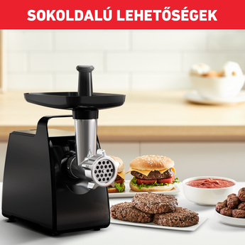 Fekete húsdaráló, hamburgerrel, húsgombóccal és hozzávalókkal az asztalon. Háttérben konyha.