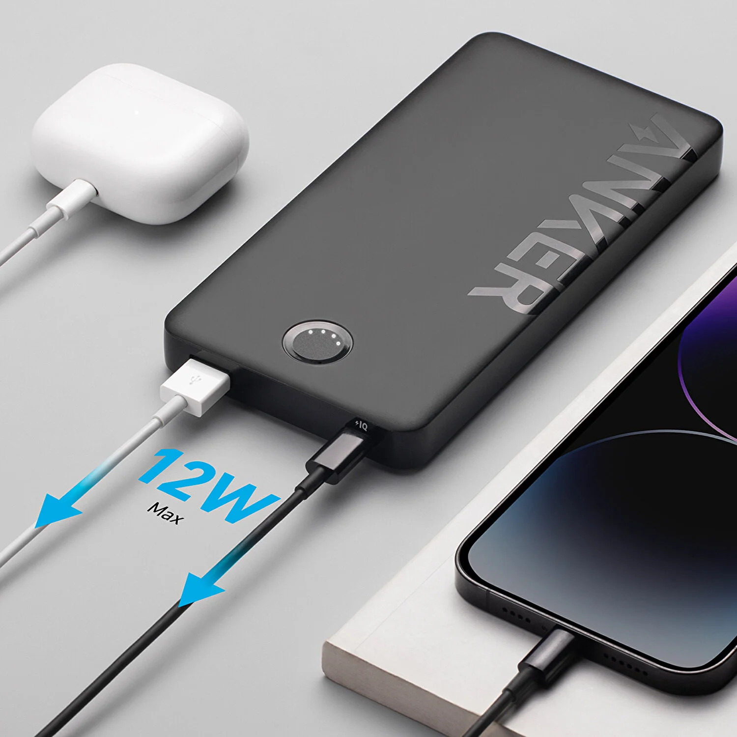 Siyah Anker powerbank, şarj olan bir telefon ve AirPods ile. Telefon, oklarla 12W Max şarj gösteriyor.