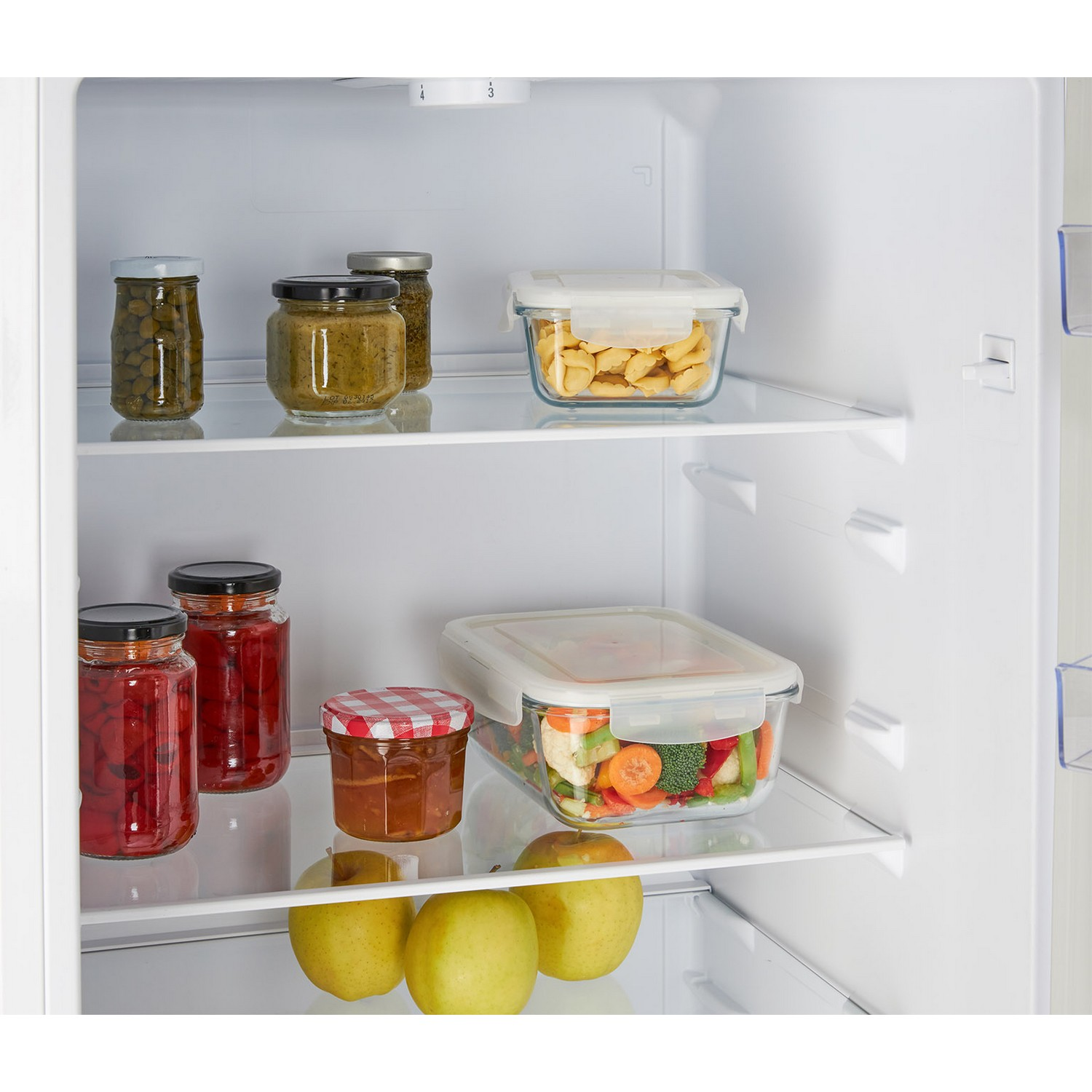 À l'intérieur d'un réfrigérateur, il y a des bocaux de nourriture, et des récipients de légumes et de fruits.