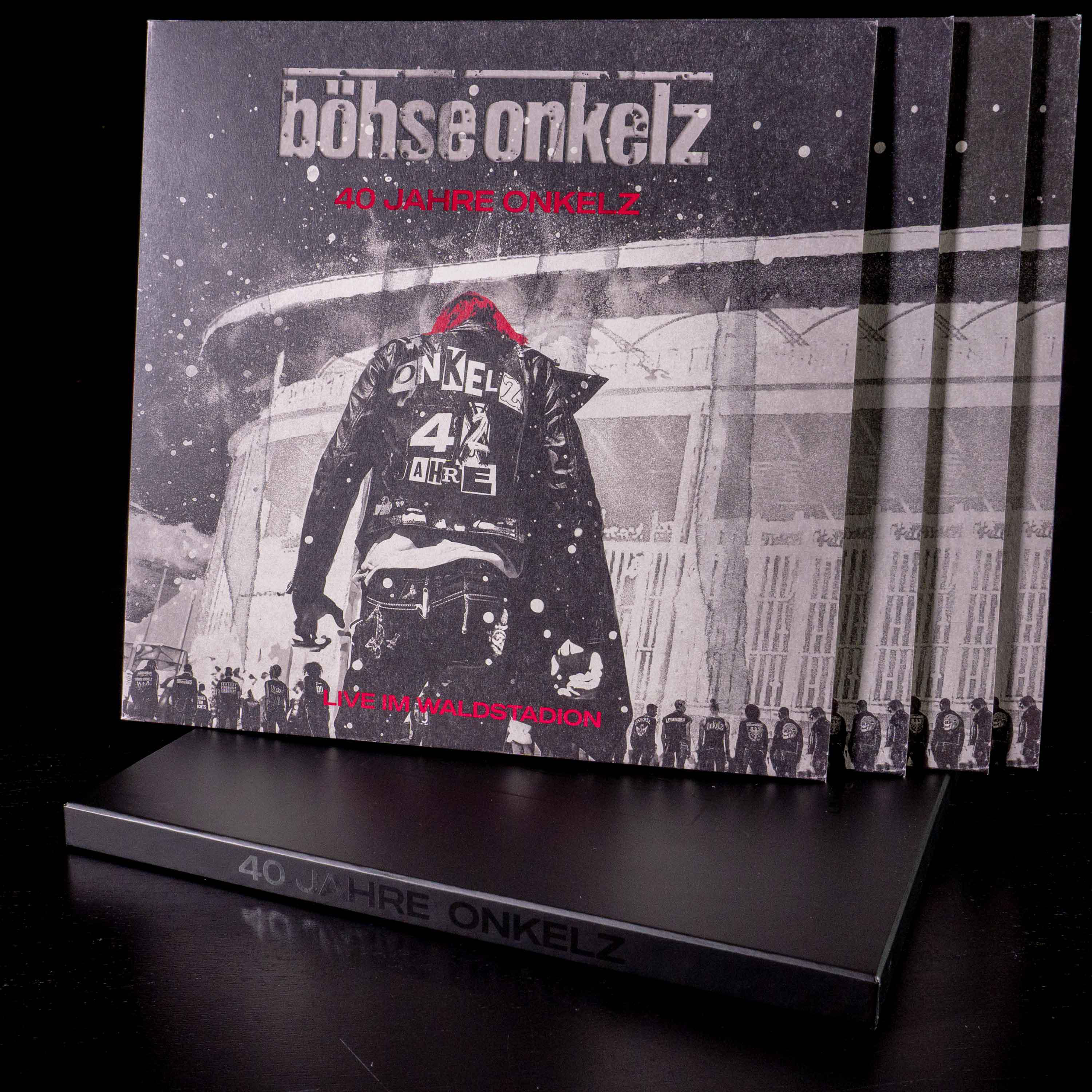 Gestapelte Albumcover, Schwarz-Weiß-Bild eines Mannes in einer Jacke, in einem Stadion.